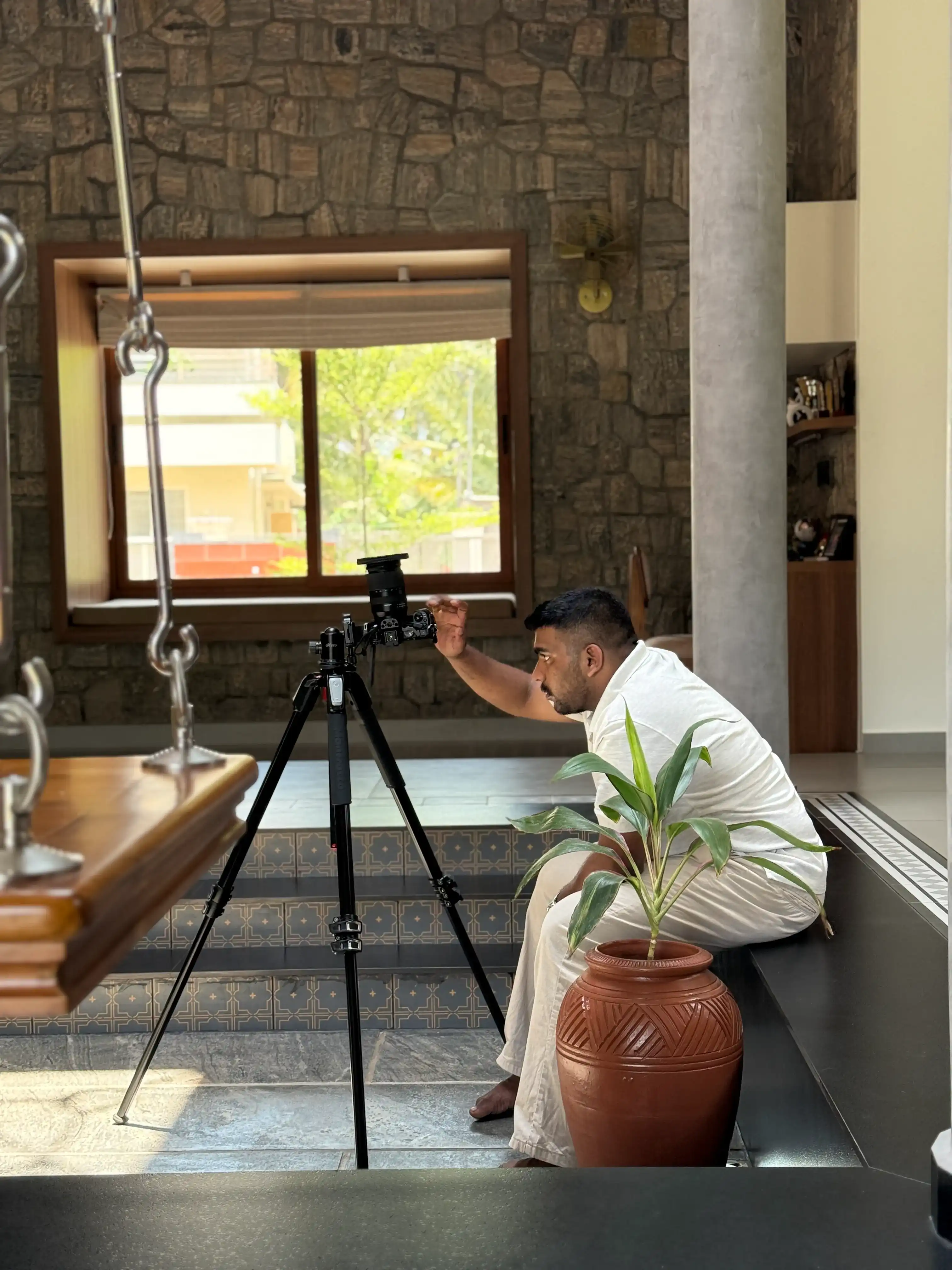 Photographer setting up camera on tripod inside a stone-walled home